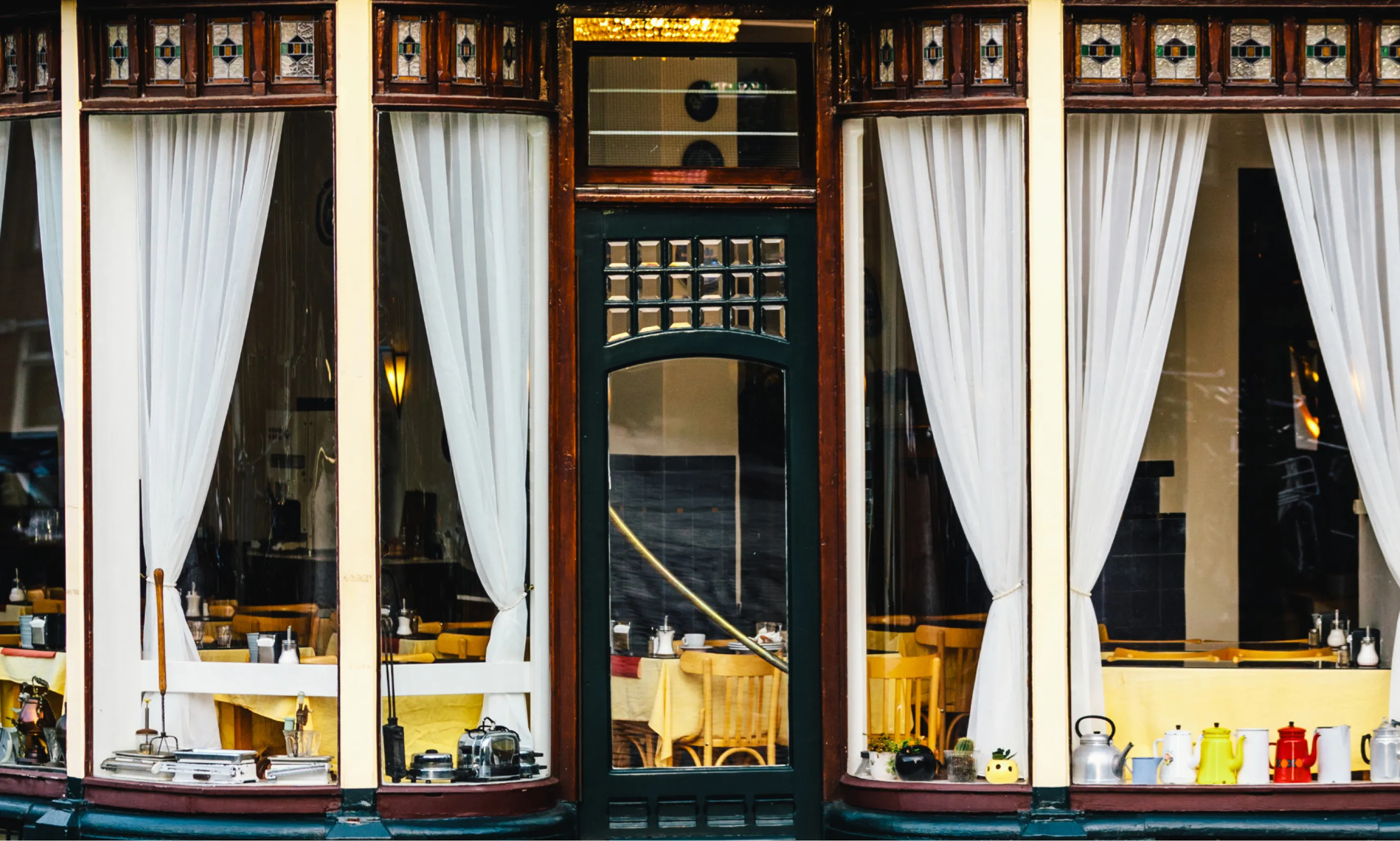 The windows of Restaurant Wiechmann on the Prinsengracht, with white net curtains and laid tables